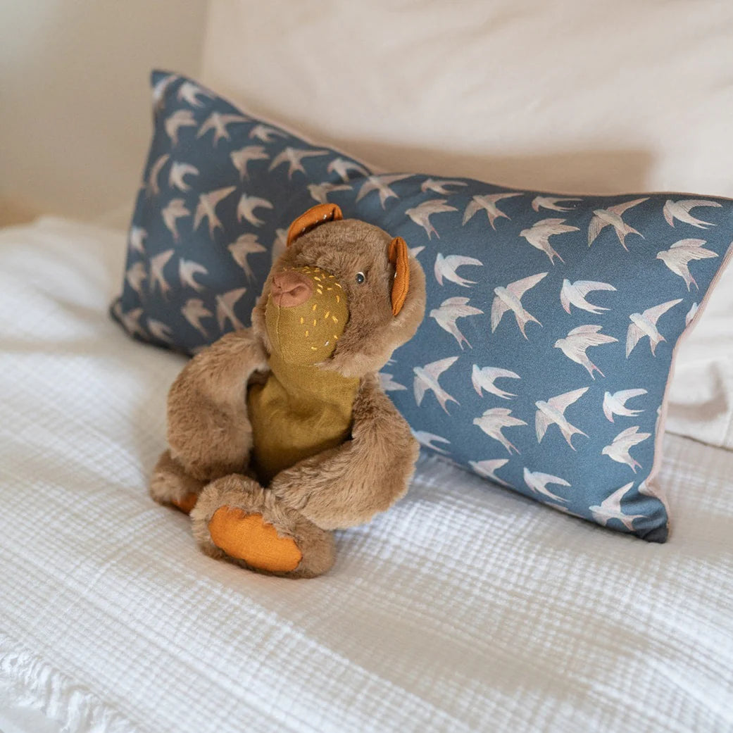 Kid's and nursery decor - Blue block print pillow with swallow bird print and a fuzzy bear stuffed animal.
