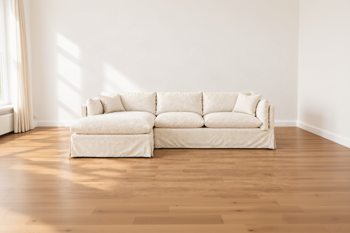 A modern three-seat sofa with a left-facing chaise lounge, upholstered in a light cream or off-white textured fabric, shown against a plain white background.